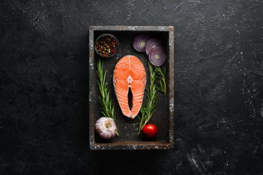 Siyah taşlı arka planda somon bifteği ve malzemeler. Üst Manzara. Metnin için boş yer.