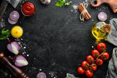 Siyah taş pişirme arka planı. Baharat ve sebze. Üst Manzara. Metnin için boş yer.