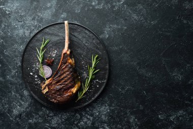 Kemiğin üzerinde biberiye ve baharatla ızgara Tomahawk bifteği. Üst Manzara. Metnin için boş yer.