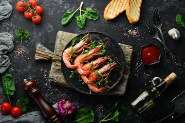 Siyah bir tabakta kaynamış karides ve roka. Deniz ürünleri tabakları. Üst Manzara. Metnin için boş yer.