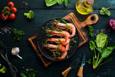 Siyah bir tabakta kaynamış karides ve roka. Deniz ürünleri tabakları. Üst Manzara. Metnin için boş yer.