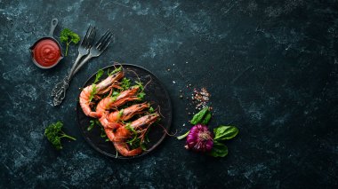 Siyah bir tabakta kaynamış karides ve roka. Deniz ürünleri tabakları. Üst Manzara. Metnin için boş yer.