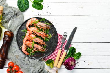 Siyah bir tabakta kaynamış karides ve roka. Deniz ürünleri tabakları. Üst Manzara. Metnin için boş yer.