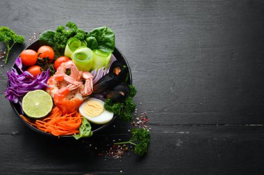 Buda kâsesi dolusu deniz ürünü. Karides, midye, lahana, vişneli domates, ıspanak. Deniz ürünleri tabakları. Üst Manzara. Metnin için boş yer.