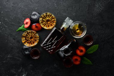 Slivovica - erik votkası, siyah taş bir masada şişedeki erik brendisi. Alkollü bardaklar. Üst Manzara. Metnin için boş yer.