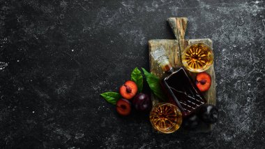 Slivovica - erik votkası, siyah taş bir masada şişedeki erik brendisi. Alkollü bardaklar. Üst Manzara. Metnin için boş yer.