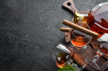 Siyah taş bir masada, bardakta konyak ve puro. Üst Manzara. Metnin için boş yer.