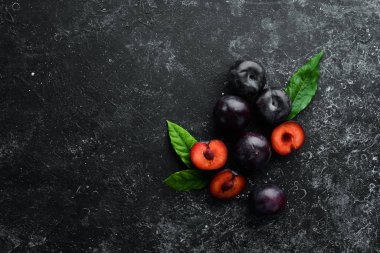 Siyah taş bir masanın üzerinde yaprakları olan taze erikler. Üst Manzara. Metnin için boş yer.