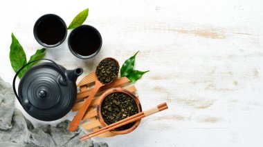 Su ısıtıcılı Çin yeşil çayı. Siyah taştan bir arka planda. Üst Manzara. Metnin için boş yer.