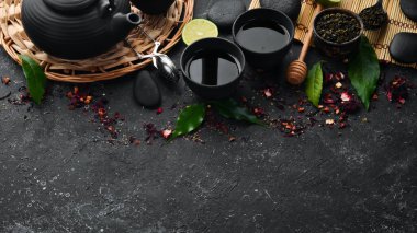 Siyah, yeşil, siyah taştan arka planda meyve ve bitki çayı. Çaydanlık ve fincanda çay. Üst Manzara. Metnin için boş yer.