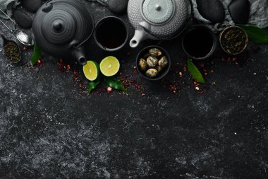 Siyah, yeşil, siyah taştan arka planda meyve ve bitki çayı. Çaydanlık ve fincanda çay. Üst Manzara. Metnin için boş yer.