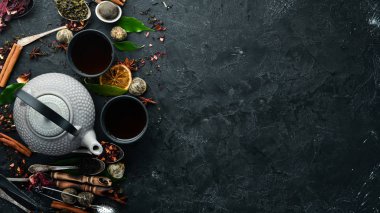 Siyah, yeşil, siyah taştan arka planda meyve ve bitki çayı. Çaydanlık ve fincanda çay. Üst Manzara. Metnin için boş yer.