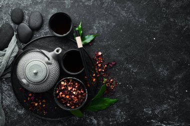 Çaydanlık ve siyah taştan bir arka planda iki fincan çay. Üst Manzara. Metnin için boş yer.