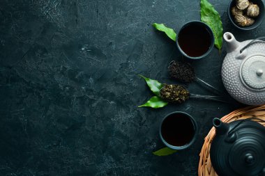 Çaydanlık ve siyah taştan bir arka planda iki fincan çay. Üst Manzara. Metnin için boş yer.