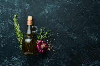 Siyah taş zemin üzerinde baharatlar olan bir şişe yağ. Üst Manzara. Boş kopyalama alanı.