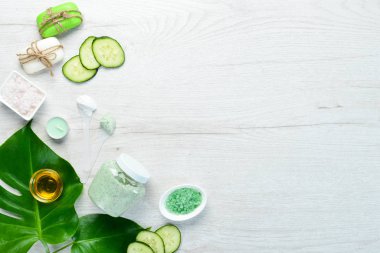 Yeşil salatalığa dayalı kozmetik ürünleri. Beyaz bir masada fırça ve vücut kremi. Üst Manzara. Metnin için boş yer.