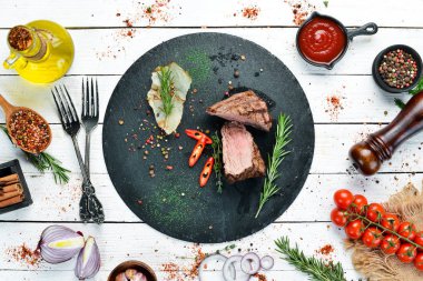 Siyah taştan bir tabakta baharatlı dana biftek. Biberli biftek. Üst görünüm, metin için boş alan. Kırsal biçim.