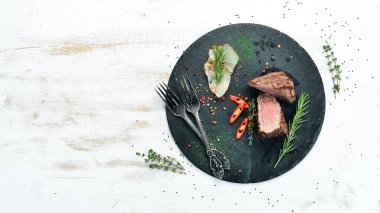 Siyah taştan bir tabakta baharatlı dana biftek. Biberli biftek. Üst görünüm, metin için boş alan. Kırsal biçim.