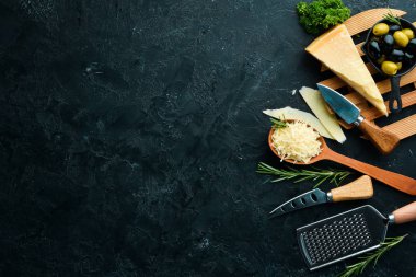 Siyah taşlı arka planda peynir bıçaklı sert peynirler. Parmesan peyniri. Üst Manzara. Metnin için boş yer.
