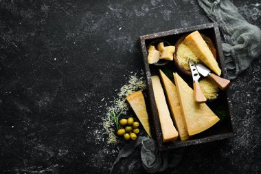 Siyah taşlı arka planda peynir bıçaklı sert peynirler. Parmesan peyniri. Üst Manzara. Metnin için boş yer.
