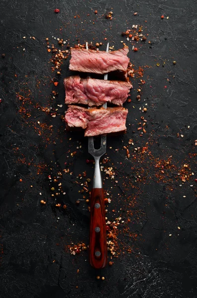 Steak Ribeye Panggang Dengan Garpu Pada Latar Belakang Batu Hitam — Stok Foto
