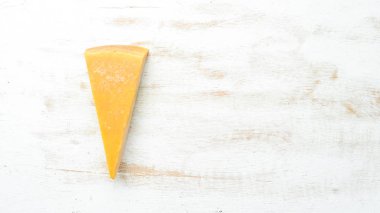 Beyaz ahşap arka planda bir parça sert peynir. Parmesan peyniri. Üst Manzara. Metnin için boş yer.