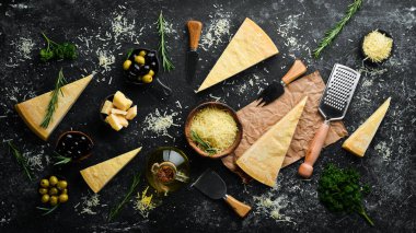 Siyah taşlı arka planda zeytin ve peynir bıçağı olan sert peynir. Parmesan peyniri. Üst Manzara. Metnin için boş yer.