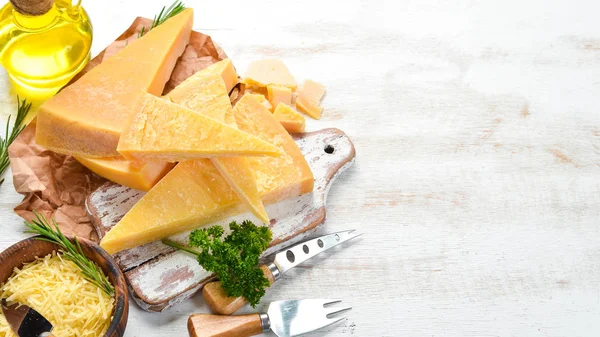 Piece of Parmesan cheese on a white wooden background. Traditional Italian cheese. Top view. Free space for your text.