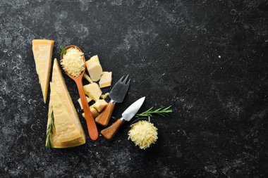 Parmesan peyniri. Siyah taş arka planda parmesan peyniri parçaları. Üst Manzara. Metnin için boş yer.