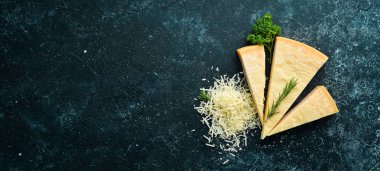 Parmesan peyniri. Siyah taş arka planda parmesan peyniri parçaları. Üst Manzara. Metnin için boş yer.