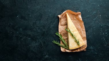 Parmesan peyniri. Siyah taş arka planda parmesan peyniri parçaları. Üst Manzara. Metnin için boş yer.