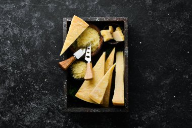 Parmesan peyniri. Siyah taş arka planda parmesan peyniri parçaları. Üst Manzara. Metnin için boş yer.