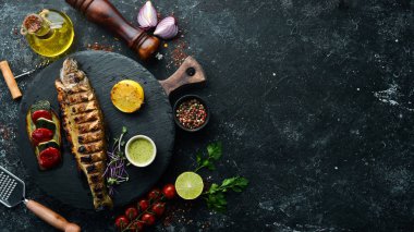 Siyah tabakta sebzeli ızgara alabalık. Üst Manzara. Metnin için boş yer. Kırsal biçim.