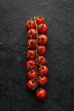 Dal üzerinde vişne domatesleri, siyah taş bir arka planda. Üst Manzara. Metnin için boş yer. Kırsal biçim.