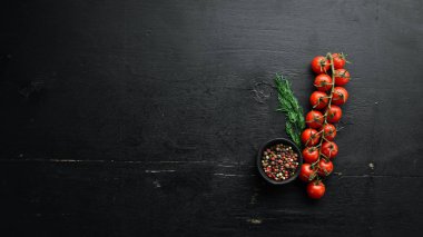 Dal üzerinde vişne domatesleri, siyah taş bir arka planda. Üst Manzara. Metnin için boş yer. Kırsal biçim.