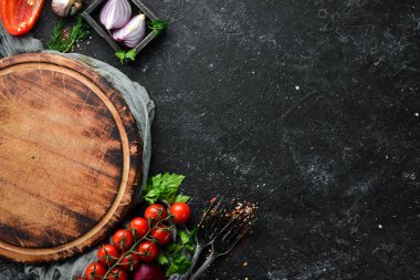 Yemek afişi. Siyah taşlı arka planda baharatlar, sebzeler ve otlar. Üst Manzara. Metnin için boş yer. Kırsal biçim.