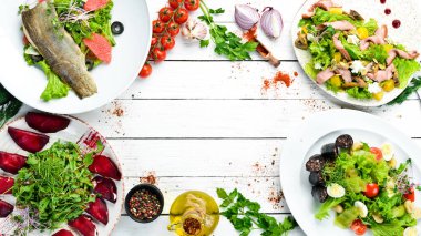 Yiyecekler. Beyaz ahşap arka planda salata ve tabaklar. Üst Manzara. Metnin için boş yer. Kırsal biçim.