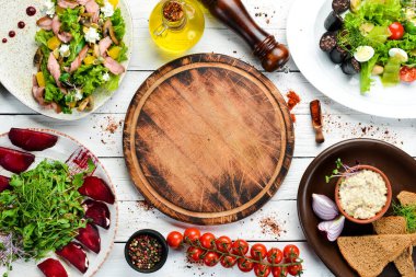 Yiyecekler. Beyaz ahşap arka planda salata ve tabaklar. Üst Manzara. Metnin için boş yer. Kırsal biçim.