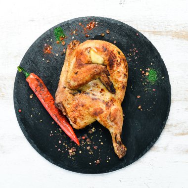 Pişmiş bıldırcın, siyah taş tabakta kırmızı biberli tavuk. Üst görünüm, metin için boş alan. Kırsal biçim.