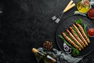 Siyah taş tabakta domates soslu ızgara sosisler. Barbekü. Üst görünüm. Ücretsiz kopyalama alanı.