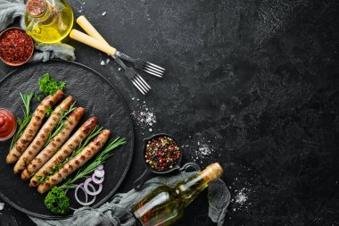 Siyah taş tabakta domates soslu ızgara sosisler. Barbekü. Üst görünüm. Ücretsiz kopyalama alanı.