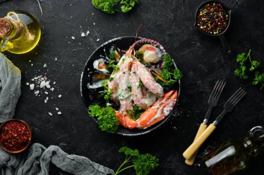 Siyah taş tabaktabaktabaktabaktabaktabaktabaktabaktabakta kremalı soslu haşlanmış deniz ürünleri. Deniz ürünleri, karides, kabuklu deniz ürünleri, ıstakoz. Üst te. Ücretsiz kopyalama alanı.