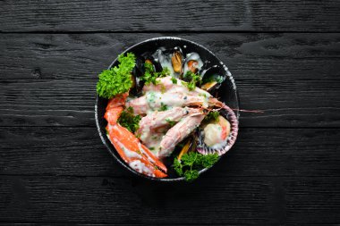 Siyah taş tabaktabaktabaktabaktabaktabaktabaktabaktabakta kremalı soslu haşlanmış deniz ürünleri. Deniz ürünleri, karides, kabuklu deniz ürünleri, ıstakoz. Üst te. Ücretsiz kopyalama alanı.