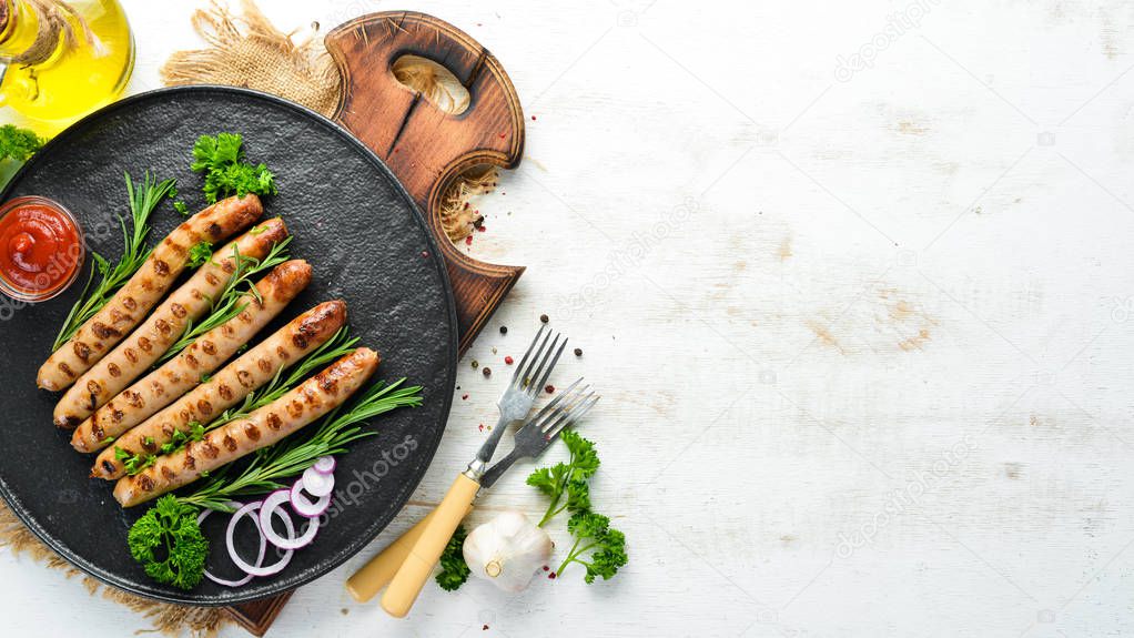 Grilled sausages with tomato sauce on a black stone plate. BBQ. Top view. Free copy space.