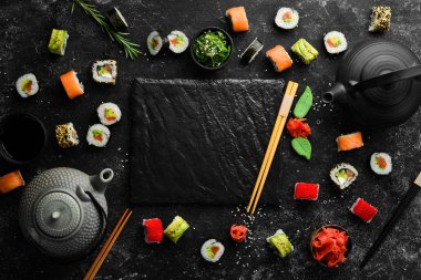 Suşi rulolarının arka planında çay, zencefil, wasabi ve soya sosu var. Japon Geleneksel Mutfağı.