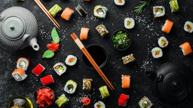 Suşi rulolarının arka planında çay, zencefil, wasabi ve soya sosu var. Japon Geleneksel Mutfağı.