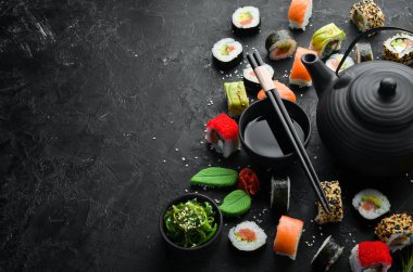 Suşi rulolarının arka planında çay, zencefil, wasabi ve soya sosu var. Japon Geleneksel Mutfağı.