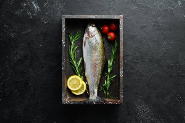 Siyah taş arka planda sebze ile çiğ balık alabalık. Üst te. Metniniz için boş alan.
