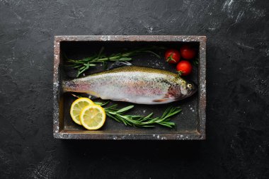 Siyah taş arka planda sebze ile çiğ balık alabalık. Üst te. Metniniz için boş alan.