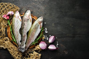 Siyah ahşap arka planda sebze li çiğ balık. Balık alabalığı. Üst te. Metniniz için boş alan.